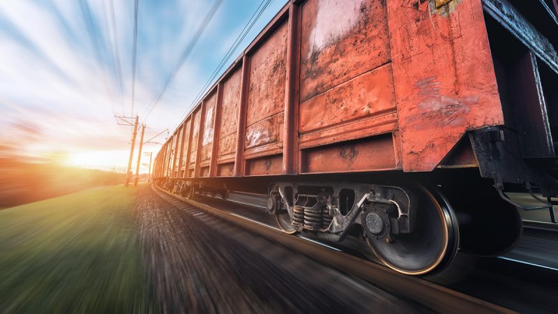 Freight train speeding along green countryside at sunset