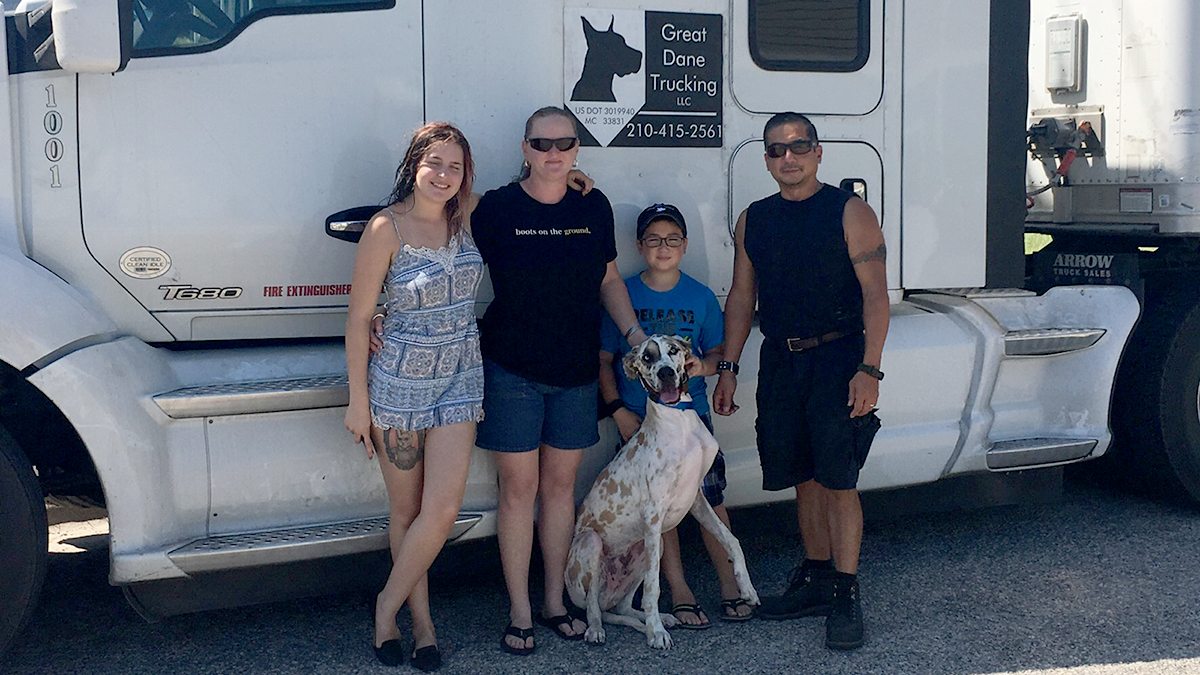 Family with dog posing in front of 18-wheeler