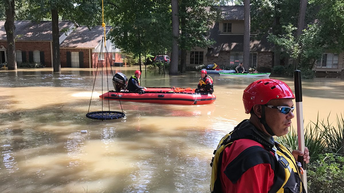 Rescue workers in an inflatable raft navigate down a flooded street