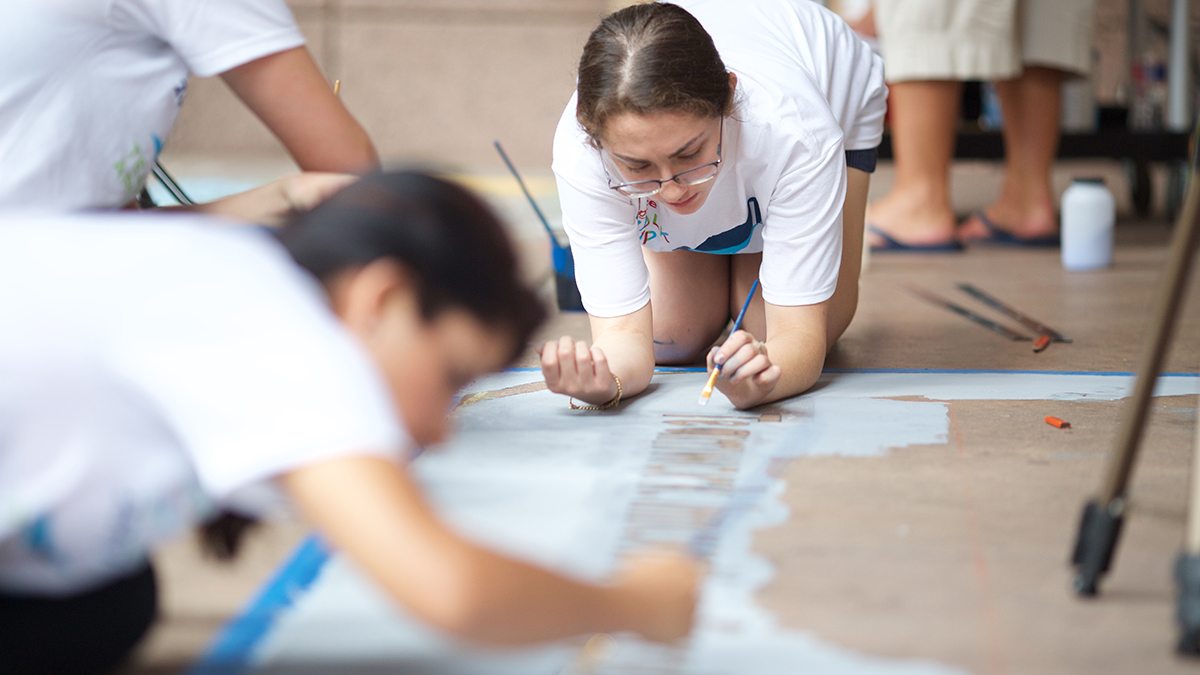 Young girl in glasses painting in letters during San Antonio's Chalk It Up event
