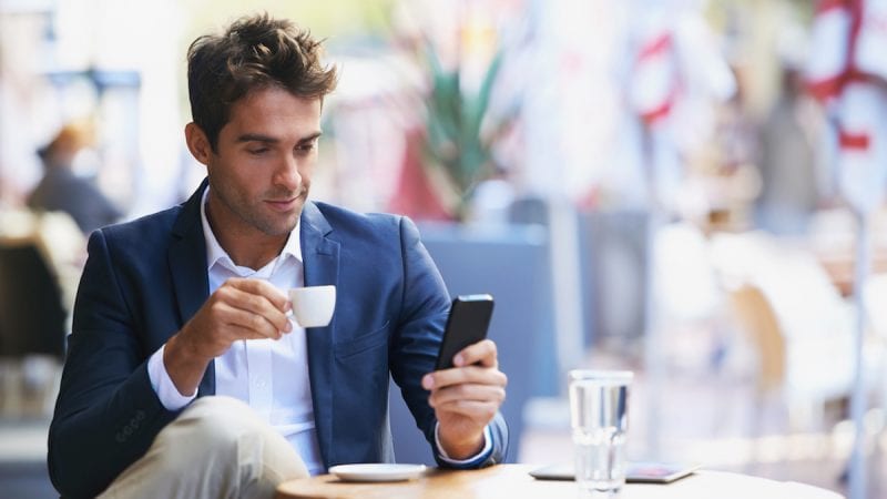 Young businessman reading a text while sitting at an outdoor cafe