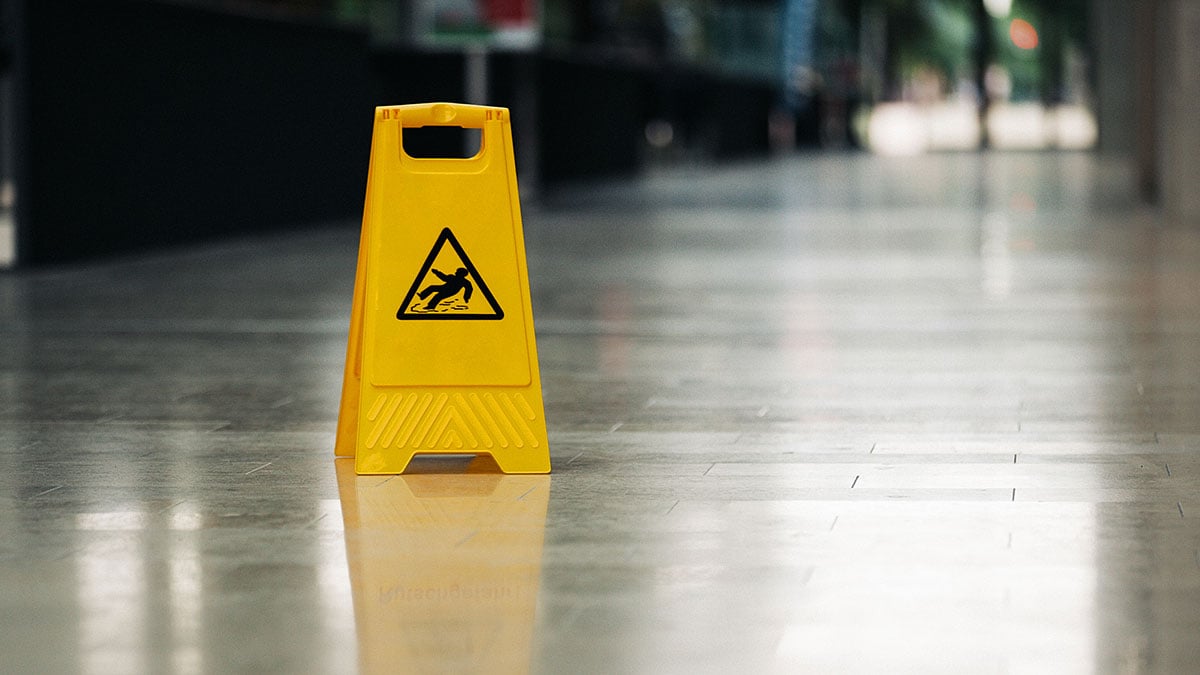 Yellow caution sign in the middle of a slippery looking floor