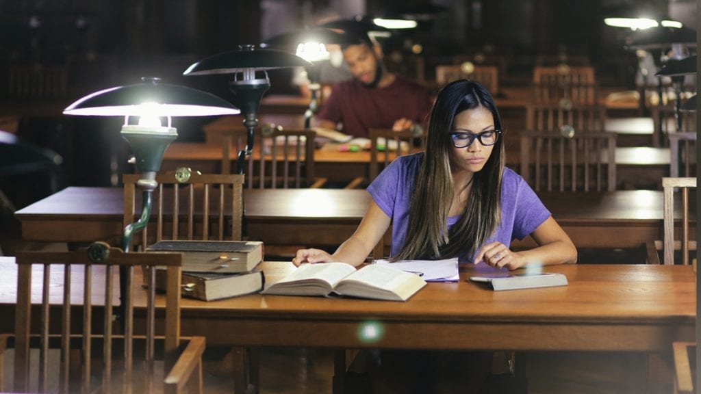 Young college student studying in a dimly-lit library